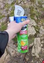 A hand holding a can of Pringles and a Redbull drink.